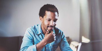 Man smiling while looking at laptop